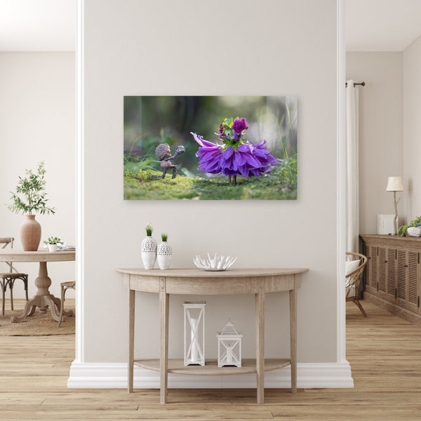 The photo of the Becorn and flower person as a metal print, mounted without a frame on a pale gray wall. The metal print faintly reflects an unseen plain wall. Underneath it is an accent table.