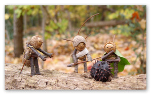 Three Becorns considering a spiky chestnut seed pod. One becorn appears to be talking, the other two look thoughtful. 