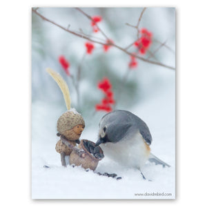 A Becorn holding a basket of seeds is looking in awe at a tufted titmouse that is picking a sunflower seed out of the basket. The ground is covered in snow, and there are a few bright red berries in the background.